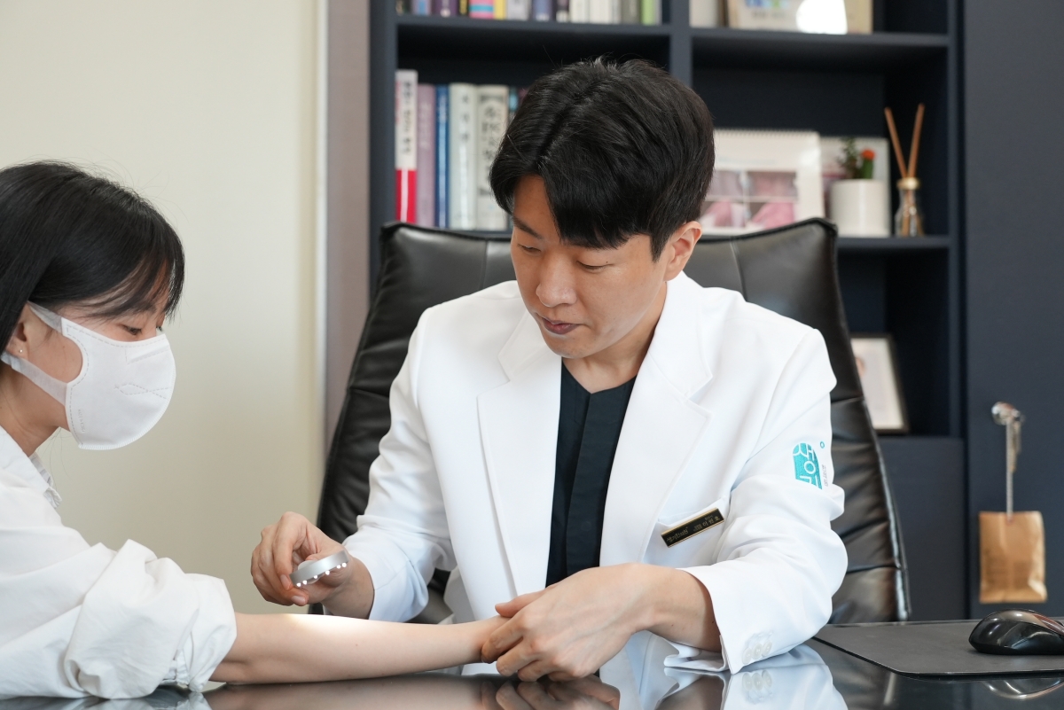 인천점 이원호 대표원장이 관찰 도구로 팔의 피부 상태를 가까이에서 살핍니다.