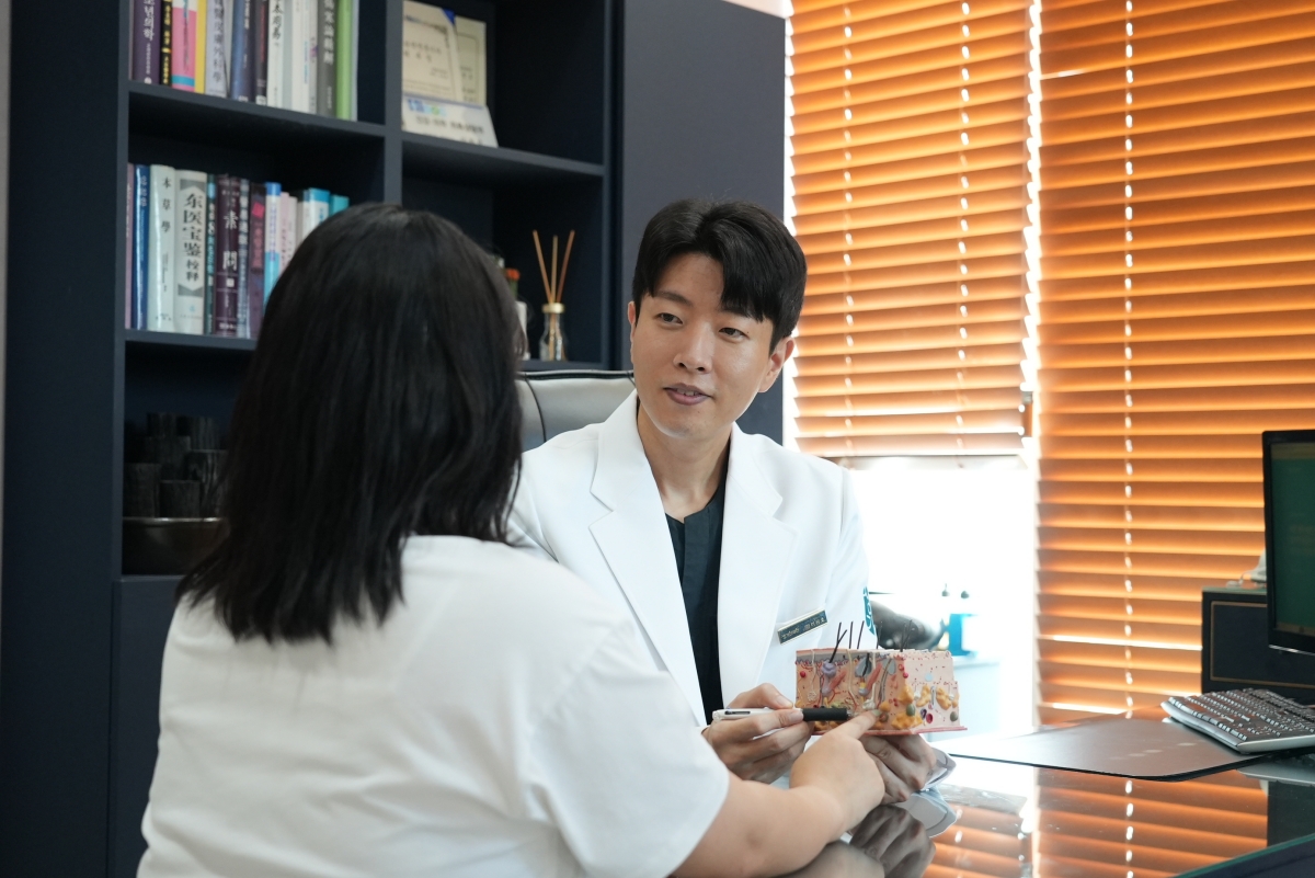 인천점 이원호 대표원장이 피부 모형을 두고 아토피가 반복되는 이유를 설명하며 상담합니다.